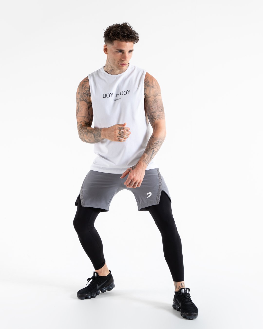 Man in white slim fit cotton muscle tank with reversed you vs you text in black on chest.