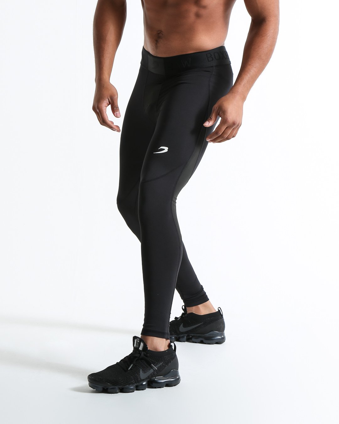 Man in black compression leggings/tights with wide elastic waistband and a white 3D strike logo on the leg.