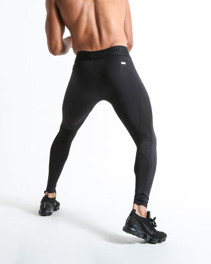 Man in black compression leggings/tights with wide elastic waistband and a white 3D strike logo on the leg.